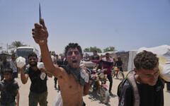 A Palestinian waves a knife and shouts to the camera in Arabic, 'We get food with the taste of death and blood,' as he carries a bag containing food and humanitarian aid packages delivered by the US- and Israel-backed Gaza Humanitarian Foundation in Rafah, southern Gaza Strip, June 10, 2025. (AP Photo/Abdel Kareem Hana)