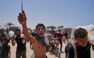A Palestinian waves a knife and shouts to the camera in Arabic, 'We get food with the taste of death and blood,' as he carries a bag containing food and humanitarian aid packages delivered by the US- and Israel-backed Gaza Humanitarian Foundation in Rafah, southern Gaza Strip, June 10, 2025. (AP Photo/Abdel Kareem Hana)