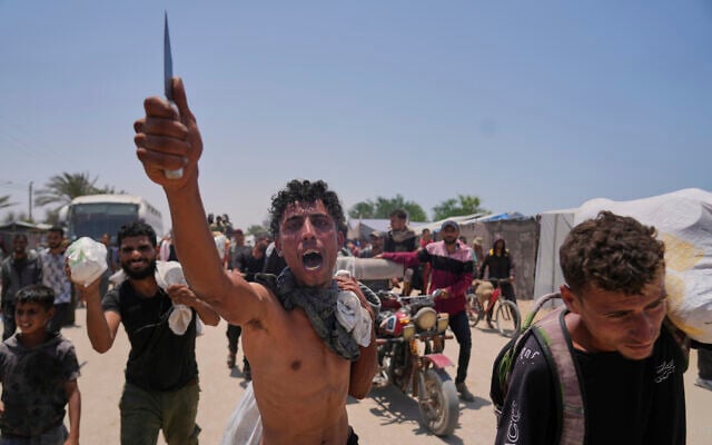 A Palestinian waves a knife and shouts to the camera in Arabic, 'We get food with the taste of death and blood,' as he carries a bag containing food and humanitarian aid packages delivered by the US- and Israel-backed Gaza Humanitarian Foundation in Rafah, southern Gaza Strip, June 10, 2025. (AP Photo/Abdel Kareem Hana)