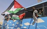 Members of a convoy en route to Gaza wave Palestinian flags from a bus as the group travels toward Egypt's Rafah Crossing, in Zawiya, Libya on June 10, 2025. (AP/Yousef Murad)