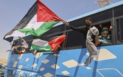 Members of a humanitarian convoy of at least 1,500 people, including activists and supporters from Algeria and Tunisia, wave Palestinian flags from a bus as the group travels toward Gaza via Egypt's Rafah Crossing, in Zawiya, Libya, Tuesday, June 10, 2025. (AP Photo/Yousef Murad)