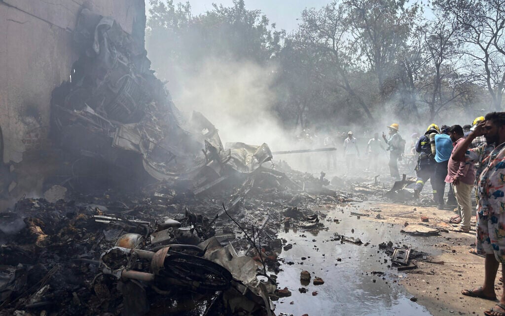 People stand around debris at the site of an airplane that crashed in India's northwestern city of Ahmedabad in Gujarat state, June 12, 2025. (AP Photo/Ajit Solanki)