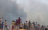 People watch smoke rising after an airplane crashed in Ahmedabad, Gujarat state, India, June 12, 2025. (Mohan Nakum via AP)
