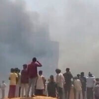 People watch smoke rising after an airplane crashed in Ahmedabad, Gujarat state, India, June 12, 2025. (Mohan Nakum via AP)