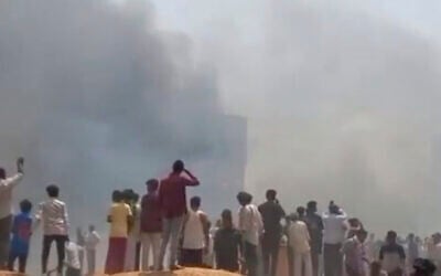 People watch smoke rising after an airplane crashed in Ahmedabad, Gujarat state, India, June 12, 2025. (Mohan Nakum via AP)