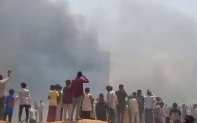 People watch smoke rising after an airplane crashed in Ahmedabad, Gujarat state, India, June 12, 2025. (Mohan Nakum via AP)