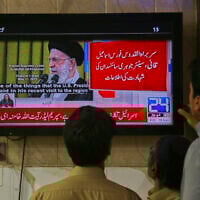 Pakistanis watch a news channel telecasting report about the Israeli attacks on Iran, in Peshawar, Pakistan, on June 13, 2025. (AP/Muhammad Sajjad)