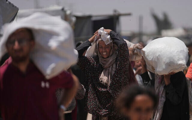 Palestinians carry bags containing food and humanitarian aid packages delivered by the Gaza Humanitarian Foundation, a US-backed organization, in Rafah, southern Gaza Strip, Monday, June 16, 2025. (AP Photo/Abdel Kareem Hana)