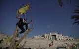 A Hezbollah supporter takes a selfie while waving a Hezbollah flag as he stands on a tree outside the Iranian Embassy in Beirut, Lebanon, June 25, 2025. (AP/Hassan Ammar)