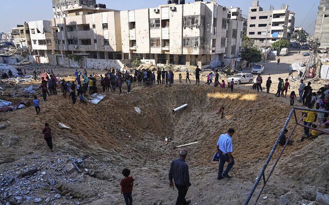Palestinians gather around a crater caused by an Israeli strike on a displacement tent camp in Gaza City, June 28, 2025. (AP/Jehad Alshrafi) Palestinians gather around a crater caused by an Israeli strike on a displacement tent camp in Gaza City, June 28, 2025. (AP/Jehad Alshrafi)