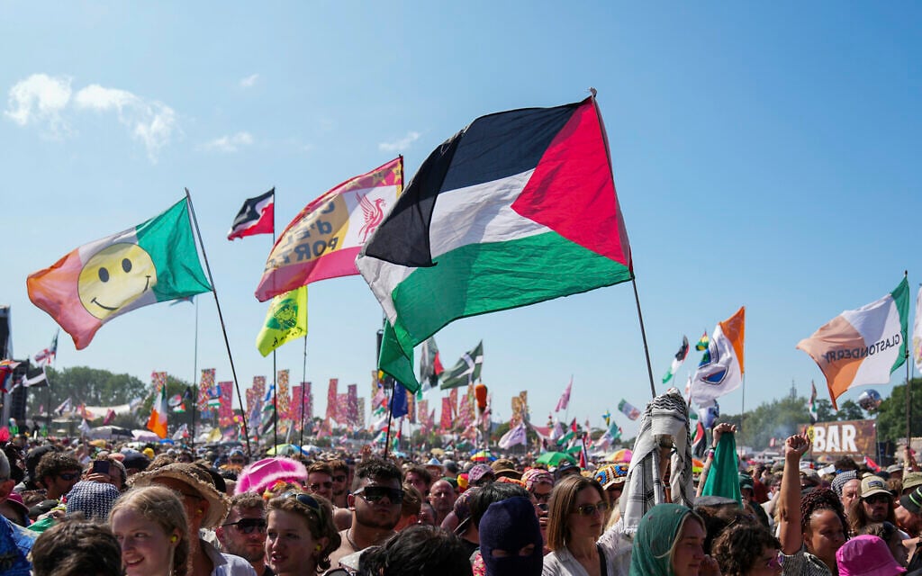 The flag of Palestine is waved in a crowd of festivalgoers at the hip hop trio Kneecap's performance during the Glastonbury Festival in Worthy Farm, Somerset, England, Saturday, June 28, 2025. (Scott A Garfitt/Invision/AP)