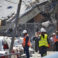 Israeli teams work to assess the damage and clear the rubble in Bnei Brak after a local school suffered a direct missile strike by Iran, June 16, 2025. (Stav Levaton/Times of Israel)