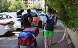 Illustrative: Clutching bags of essentials, Petah Tikva residents evacuate homes shattered by Iranian missile strike, June 16, 2025. (Stav Levaton/Times of Israel)