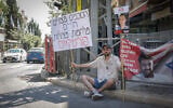 An Israeli protester sits outside Prime Minister Benjamin Netanyahu's residence, calling for the return of the Israeli hostages and an end to the war, on June 13, 2025. His sign reads: "Agreements save lives. Wars save politicians." (Rachel Alroey/FLASH90)