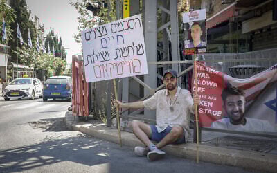 An Israeli protester sits outside Prime Minister Benjamin Netanyahu's residence, calling for the return of the Israeli hostages and an end to the war, on June 13, 2025. His sign reads: "Agreements save lives. Wars save politicians." (Rachel Alroey/FLASH90)