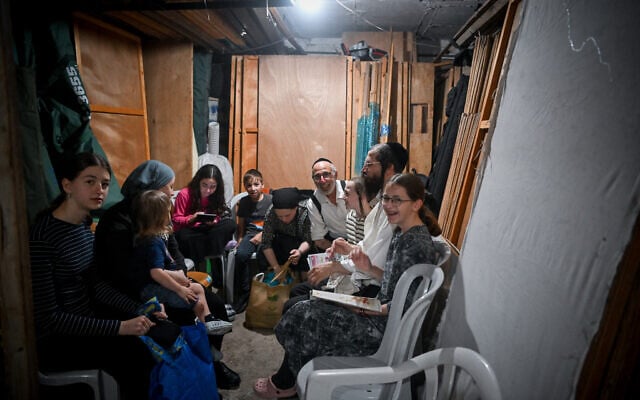 People take cover as siren warns of incoming missiles fired from Iran, at a public bomb shelter in Jerusalem on June 15, 2025. (Arie Leib Abrams/Flash90)