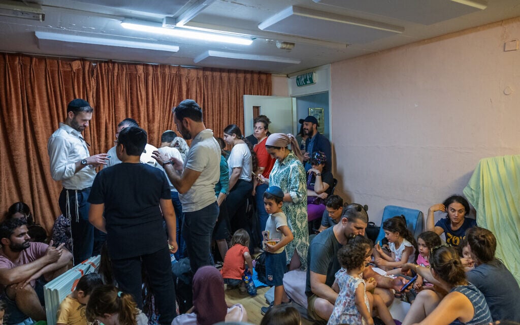 People take cover as siren warns of incoming missiles fired from Iran, at a public bomb shelter in Jerusalem on June 15, 2025. (Noam Revkin Fenton/Flash90)