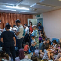 People take cover as siren warns of incoming missiles fired from Iran, at a public bomb shelter in Jerusalem on June 15, 2025. (Noam Revkin Fenton/Flash90)