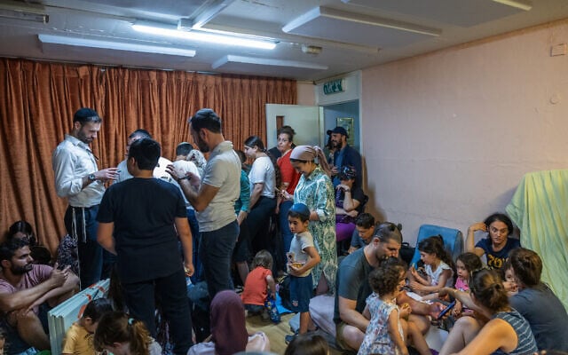 People take cover as siren warns of incoming missiles fired from Iran, at a public bomb shelter in Jerusalem on June 15, 2025. (Noam Revkin Fenton/Flash90)