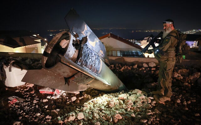 A soldier stands next to a remnant of an Iranian missile in the city of Safed on June 16, 2025. (David Cohen/Flash90)