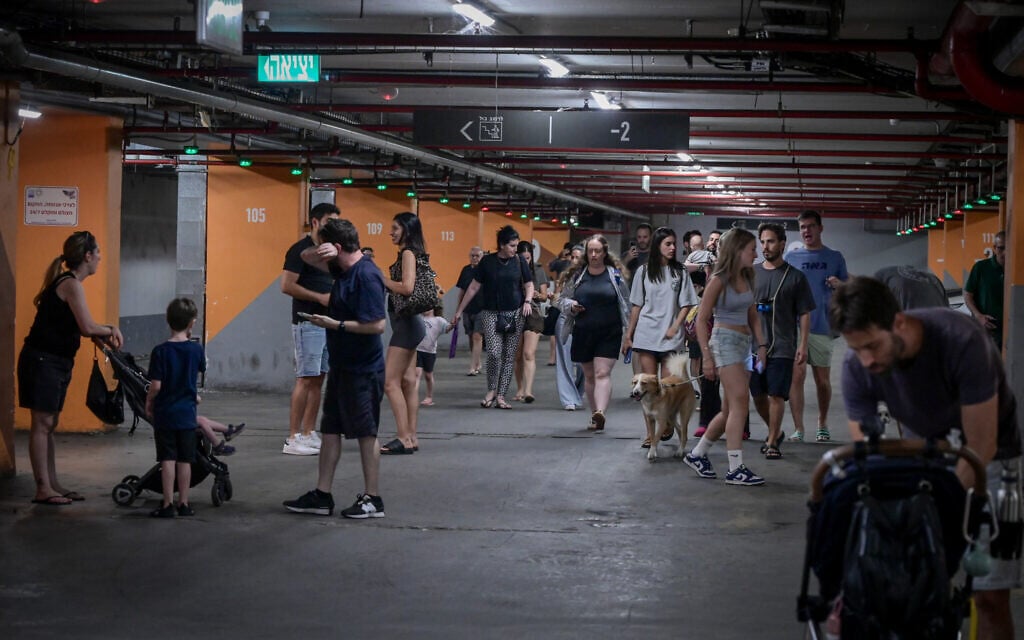 Israelis take cover in an underground parking lot in Tel Aviv, as a siren is heard warning of incoming ballistic missiles fired from Iran, June 17, 2025. (Avshalom Sassoni/Flash90)