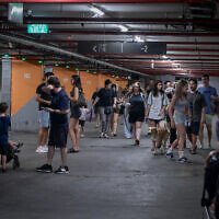 Israelis take cover in an underground parking lot in Tel Aviv, as a siren is heard warning of incoming ballistic missiles fired from Iran, June 17, 2025. (Avshalom Sassoni/Flash90)