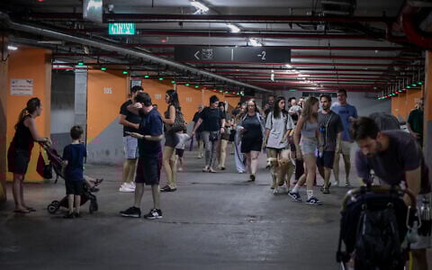 Israelis take cover in an underground parking lot in Tel Aviv, as a siren is heard warning of incoming ballistic missiles fired from Iran, June 17, 2025. (Avshalom Sassoni/Flash90)