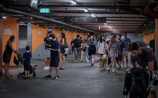 Israelis take cover in an underground parking lot in Tel Aviv, as a siren is heard warning of incoming ballistic missiles fired from Iran, June 17, 2025. (Avshalom Sassoni/Flash90)