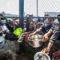 Palestinians wait to receive a hot meal prepared by volunteers, in Khan Younis, in the southern Gaza Strip, June 20, 2025. (Abed Rahim Khatib/Flash90)