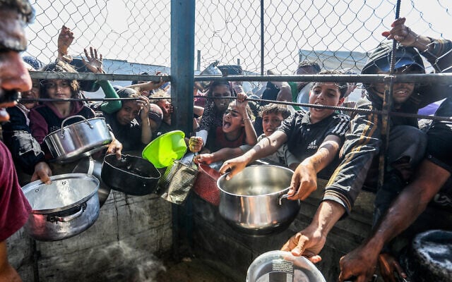 Palestinians wait to receive a hot meal prepared by volunteers, in Khan Younis, in the southern Gaza Strip, June 20, 2025. (Abed Rahim Khatib/Flash90)