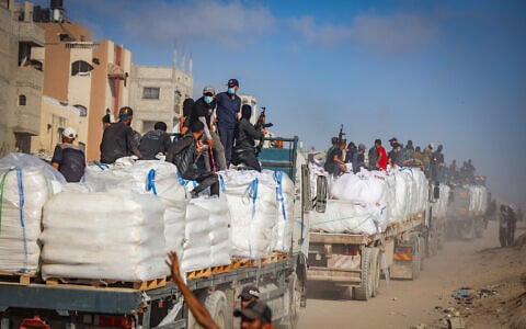 Illustrative: Armed Palestinians sit on trucks carrying humanitarian aid near the Zikim border crossing between Israel and Beit Lahia in the northern Gaza Strip, June 25, 2025. (Ali Qariqa/Flash90)