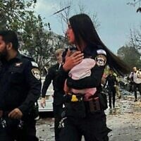 A police officer holds a three-month-old baby after it was pulled from the ruins of a home hit by an Iranian missile in Rishon Letzion on June 14, 2025 (Israel Police)