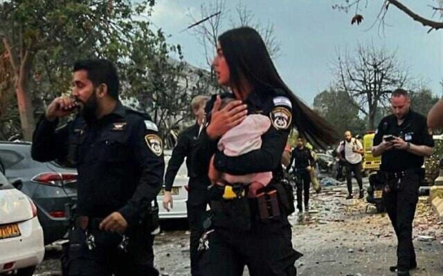 A police officer holds a three-month-old baby after it was pulled from the ruins of a home hit by an Iranian missile in Rishon Letzion on June 14, 2025 (Israel Police)