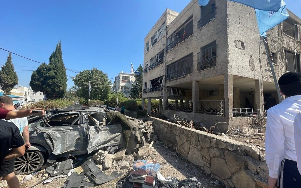 Debris and a burned out car on the sidewalk of a residential building damaged by shockwaves from the explosion of an Iranian missile in the northern city of Haifa on June 15, 2025, photographed on June 16, 2025. (Sue Surkes/Times of Israel)