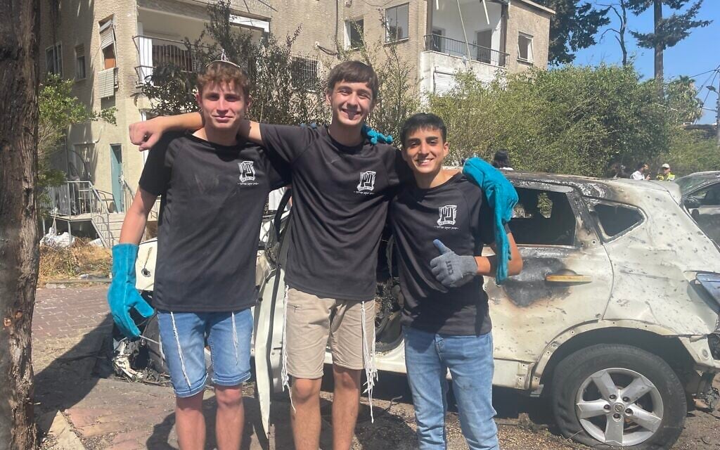 Three Bnei Akiva boys volunteer to clear debris following an explosion of an Iranian missile in the northern city of Haifa on June 15, 2025, photographed on June 16, 2025. (Sue Surkes/Times of Israel)