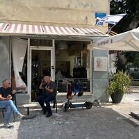 Patrons of a cafe whose windows were shattered by a nearby missile impact sit next to piles of broken glass, Tel Aviv, June 16, 2025. (Niv Elis/ JTA)