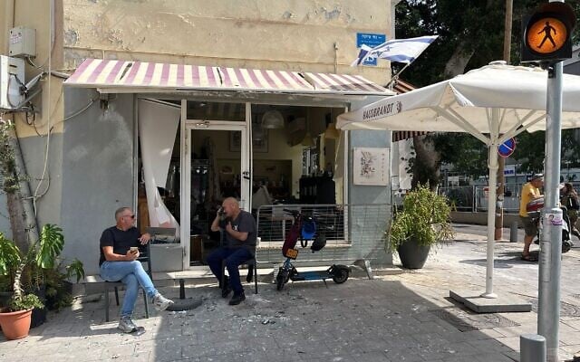 Patrons of a cafe whose windows were shattered by a nearby missile impact sit next to piles of broken glass, Tel Aviv, June 16, 2025. (Niv Elis/ JTA)