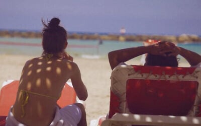 A couple on the beach in Tel Aviv, the night after the first barrages of retiliatory strikes from Iran, June 14, 2025. (Eli Katzoff)