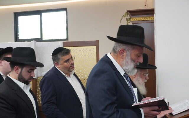 Shas party chairman Aryeh Deri prays the afternoon mincha prayer alongside former Sephardic chief rabbi Yitzhak Yosef in Jerusalem's Or Habib Synagogue after the building was torched in an arson attack on June 8, 2025. (Charlie Summers/Times of Israel)
