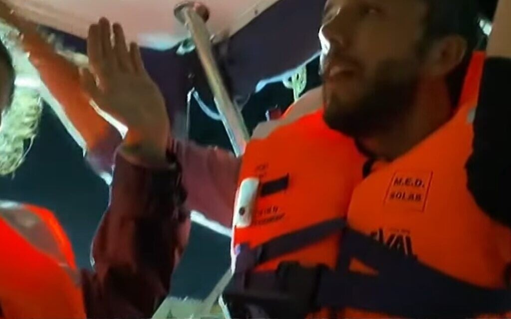 Activists aboard the Madleen holding their hands up in video taken on June 9, 2025. (screen capture: Al Jazeera/YouTube)