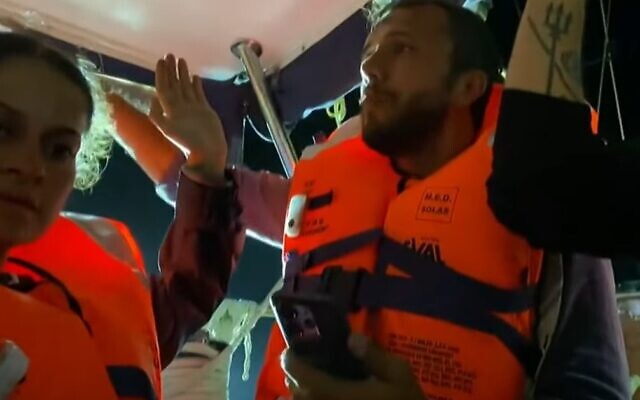 Activists aboard the Madleen holding their hands up in video taken on June 9, 2025. (screen capture: Al Jazeera/YouTube)