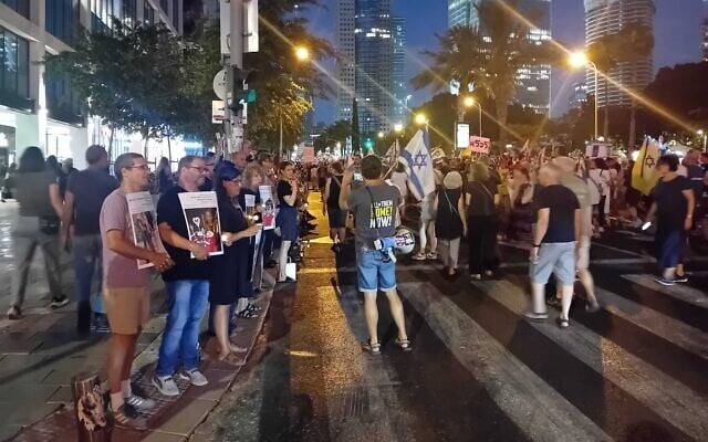 Left-wing activists hold up candles and pictures of slain Gaza children as protesters march from one anti-government protest to another, on Tel Aviv's Kaplan Street, July 5, 2025. Hadash MK Ofer Cassif is second from the left. (Noam Lehmann/The Times of Israel)