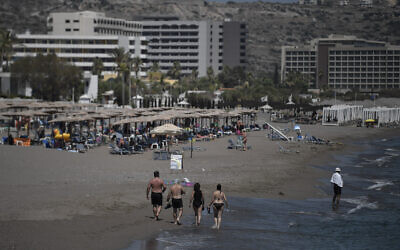 Tourists walk on the beach in front of hotels on the Aegean island of Rhodes on August 29, 2020. (Louisa GOULIAMAKI / AFP)
