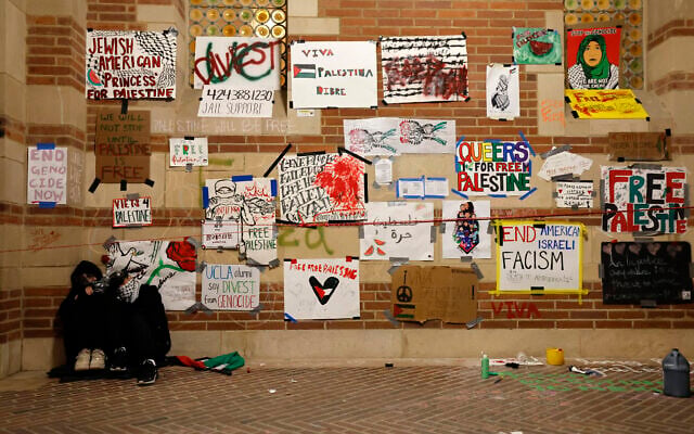 A couple of protesters sleep beneath a wall covered with placards near an encampment set up by pro-Palestinian students and activists on the campus of the University of California, Los Angeles (UCLA) in Los Angeles, California, on May 1, 2024. (Etienne LAURENT / AFP) A couple of protesters sleep beneath a wall covered with placards near an encampment set up by pro-Palestinian students and activists on the campus of the University of California, Los Angeles (UCLA) in Los Angeles, California, on May 1, 2024. (Etienne LAURENT / AFP)