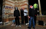 Protesters inside an encampment set up by pro-Palestinian students and activists wrap scarves on their faces as they demonstrate on the campus of the University of California, Los Angeles (UCLA) in Los Angeles, California, on May 1, 2024. (Etienne Laurent/AFP)