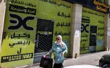 A woman walks past the closed offices of the Alkhalej Exchange Company in Ramallah on May 16, 2024. (JAAFAR ASHTIYEH / AFP)