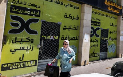 A woman walks past the closed offices of the Alkhalej Exchange Company in Ramallah on May 16, 2024. (JAAFAR ASHTIYEH / AFP)