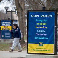 University of Michigan students walk on the UM campus next to signage displaying the university's 'core values,' on April 3, 2025, in Ann Arbor, Michigan. (BILL PUGLIANO / GETTY IMAGES NORTH AMERICA / Getty Images via AFP)