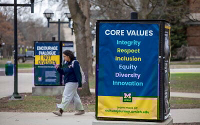 University of Michigan students walk on the UM campus next to signage displaying the university's 'core values,' on April 3, 2025, in Ann Arbor, Michigan. (BILL PUGLIANO / GETTY IMAGES NORTH AMERICA / Getty Images via AFP)