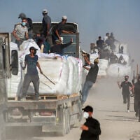 Volunteers from Palestinian families guard trucks carrying aid that entered the Gaza Strip from the Zikim border crossing, June 25, 2025. (Bashar TALEB / AFP)